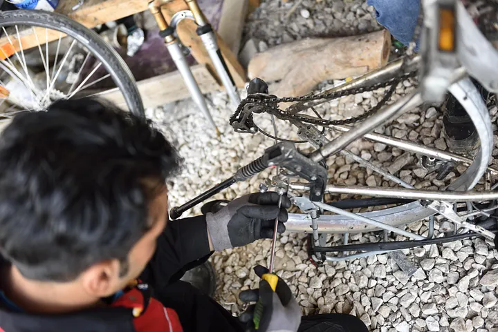 Ali réparant un vélo au Low-tech Makerspace d'EKO! à Lesbos ©2019Ralf Henning